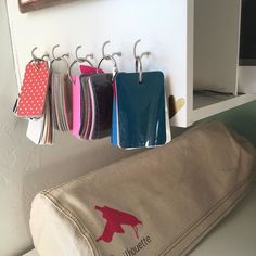 several bags hanging from hooks on the wall next to a bag with tags in it