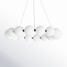 a light fixture hanging from the ceiling with many white balls on each end and black cord