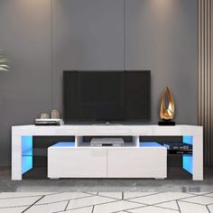 a white entertainment center with blue lights on the sides and a flat screen tv mounted to it's side