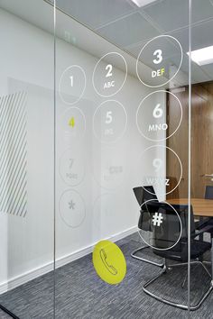 an office meeting room with glass walls and round numbers on the wall, as well as a yellow frisbee