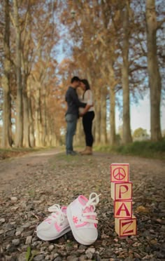 a couple standing next to each other in the woods with their shoes on the ground