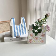 a flower in a vase sitting on top of a white table next to a book