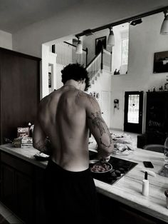 a shirtless man is cooking in the kitchen