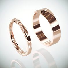 two gold wedding bands with diamonds on each side and one in the middle, against a white background