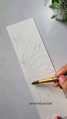 someone is drawing on paper with a brush