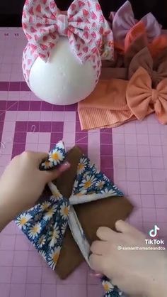 someone is cutting out fabric with scissors and bows on the table next to some other items