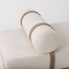 an upholstered white couch with brown straps