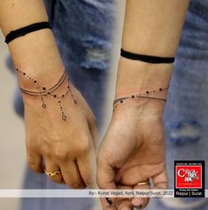 two people holding hands with small tattoos on their wrist and wristbands that are connected to each other