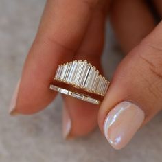 a woman's hand holding a gold ring with three baguettes on it