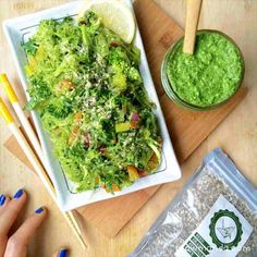 a salad with broccoli, lettuce and lemon wedges on a cutting board