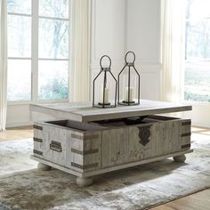 an old trunk coffee table with two candles on it in front of a large window