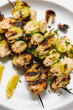 grilled brussel sprouts on a white plate with lemon wedges