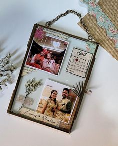 a couple hanging from a chain on top of a table next to a vase with flowers