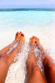 two people laying in the water with their feet up