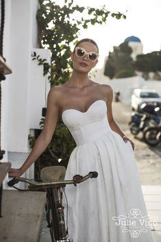 a woman in a white dress standing next to a bike