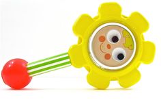 a yellow toy with two eyes and a red ball in front of it on a white background