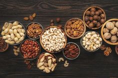 nuts in bowls on a wooden table with the top one open to show different types of nuts