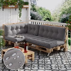 a couch and coffee table on a porch with potted plants next to it,