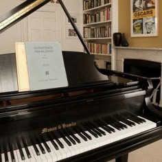 a black piano with a book on it in front of a bookshelf filled with books