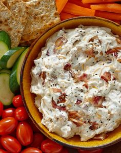 a bowl of dip surrounded by vegetables and crackers