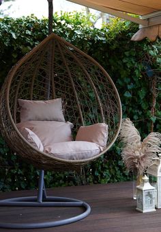 a hanging egg chair with pillows on the back and cushions on the front, along with other outdoor furniture