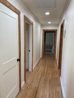 an empty hallway with wooden floors and white walls