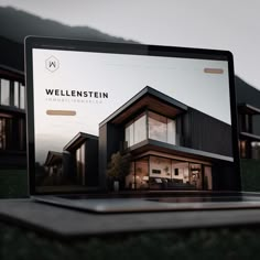 an open laptop computer sitting on top of a wooden table in front of a house