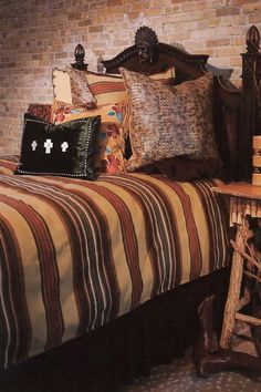 a bed with striped sheets and pillows next to a brick wall