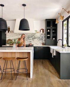 a woman sitting at a kitchen island with two stools in front of the counter