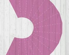 the letter c is made up of pink and white lines on a wooden background with an arrow in the center