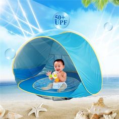 a baby sitting in a blue tent on the beach