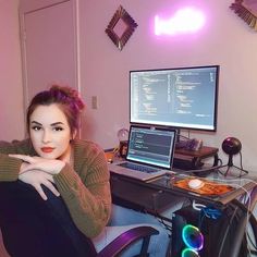 a woman sitting in front of a computer desk with a laptop on top of it