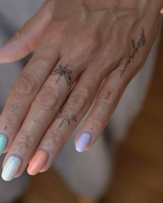 a woman's hand with two different colored nail polishes and a spider tattoo on it