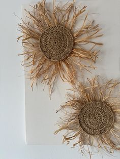 two sunflowers made out of straw are hanging on the wall