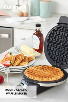 waffle maker with syrup, butter and strawberries on the counter next to it