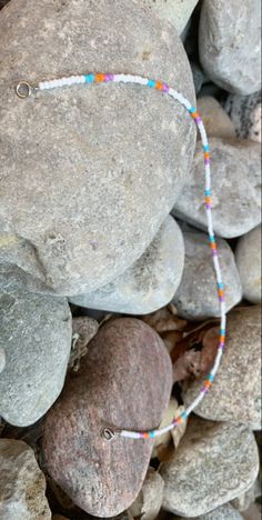 a bracelet is sitting on some rocks and has beads around the clasp that are attached to it