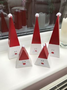 three red and white santa hats sitting on top of a window sill