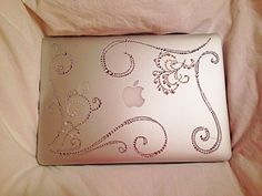 an apple laptop covered in swarong on a white bed sheet with a pink comforter