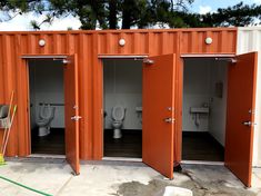 three toilets are in an orange container with doors open to reveal the toilet stalls inside