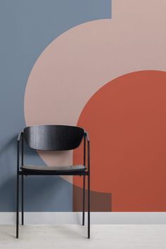 a chair sitting in front of a wall with an abstract design