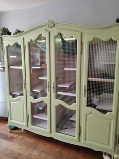 a green china cabinet with glass doors on top