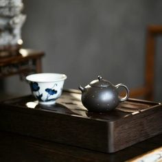 a tea pot and two cups on a tray