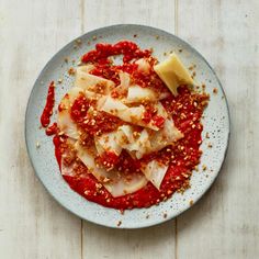 a white plate topped with ravioli covered in red sauce and parmesan cheese