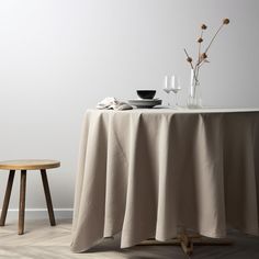 the table is set for two with plates and glasses on it, next to a small stool