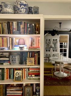 a bookshelf filled with lots of books next to a dining room table and chairs