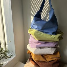 a stack of folded clothes sitting on top of a window sill next to a plant