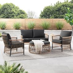 an outdoor seating area with black cushions and wicker furniture