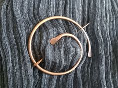 a pair of gold hoop earrings sitting on top of a gray blanket