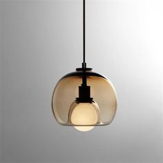 a glass light hanging from a ceiling fixture with a black cord and an orange bulb