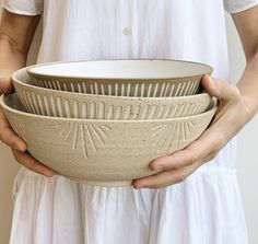 a person holding two bowls in their hands, one is white and the other is beige